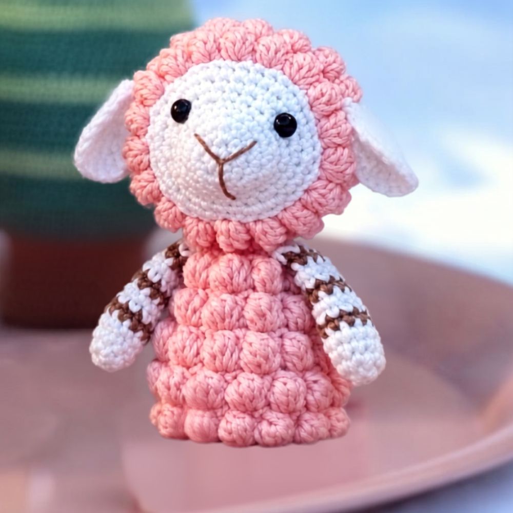 Schaap amigurumi van de Wolplein x Mrs. Milly KerstCAL 2026 met roze bobbelsteek